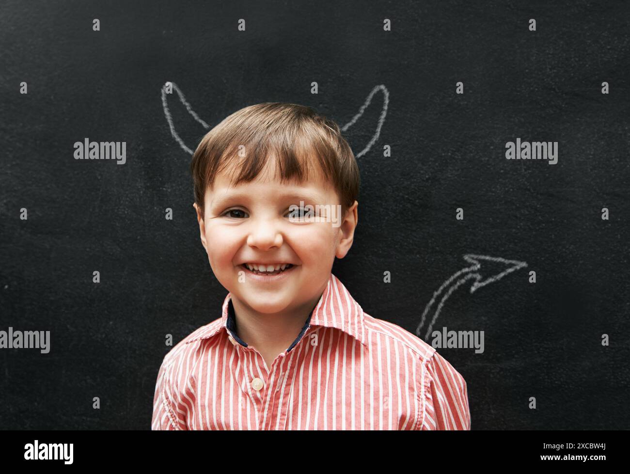 Child, portrait and chalk with devil on board with smile in class ...