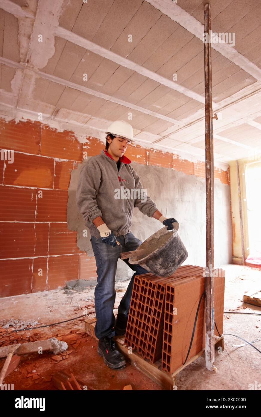 Bricklayer with trowel, bricks, new homes under construction, construction site Stock Photo