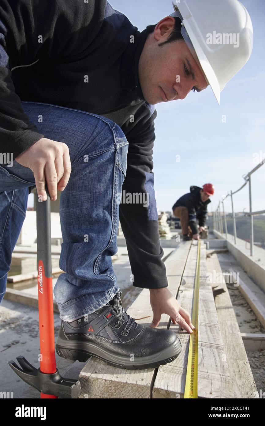 Construction workers measuring, personal protective equipment, housing construction Stock Photo