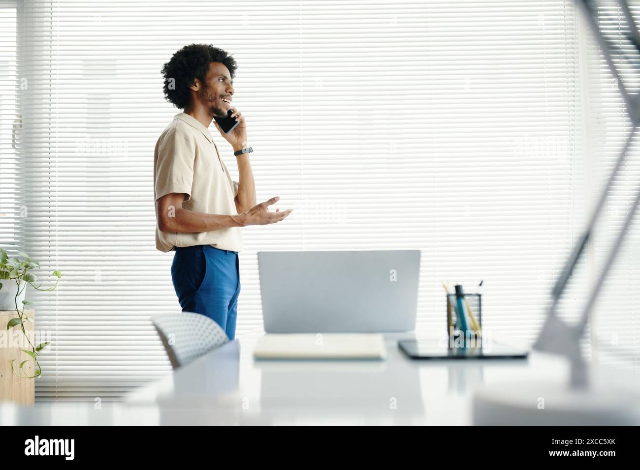 Businessman walking in his office and talking on phone Stock Photo