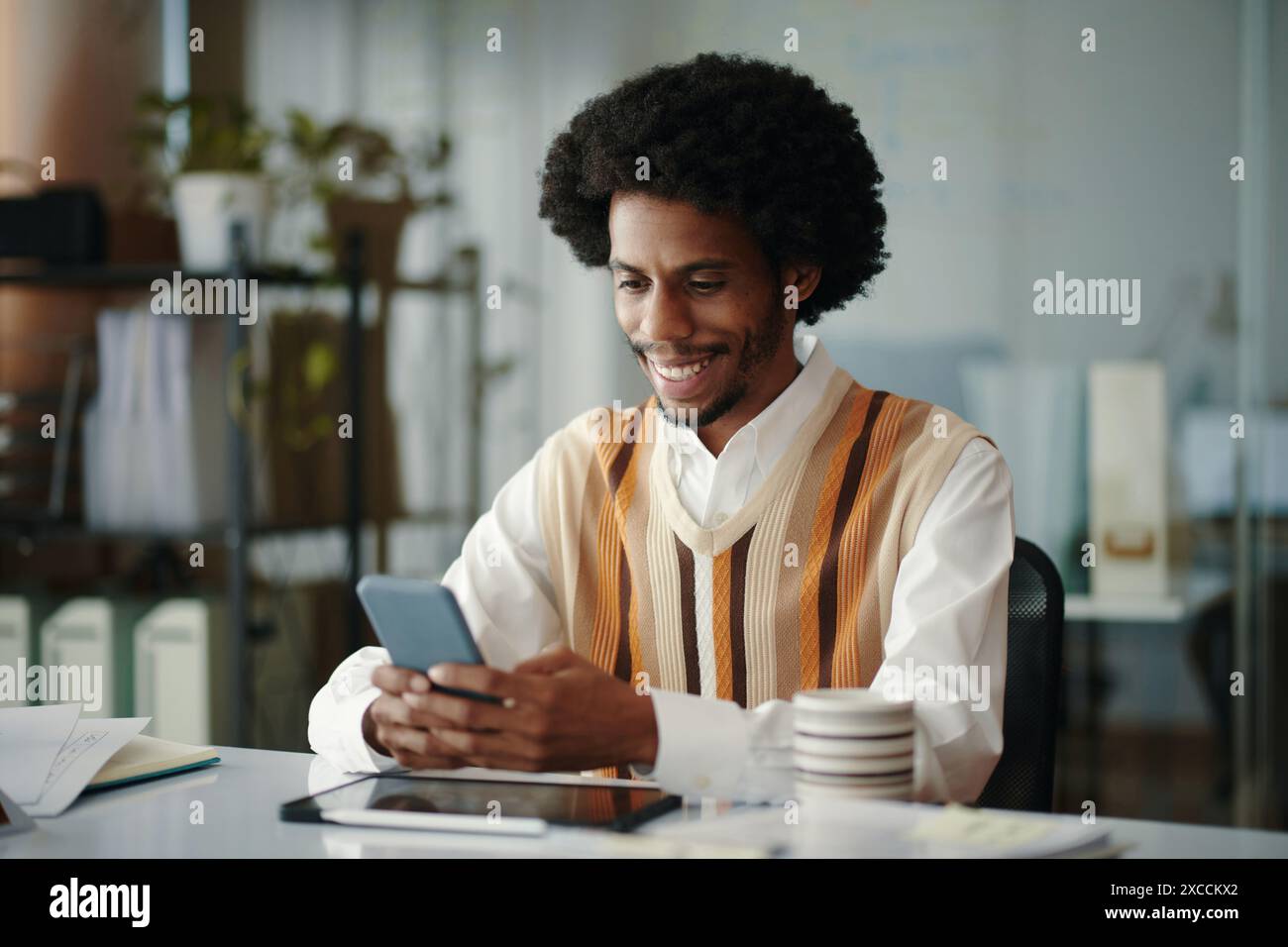 Smiling engineer answering text messages from client Stock Photo