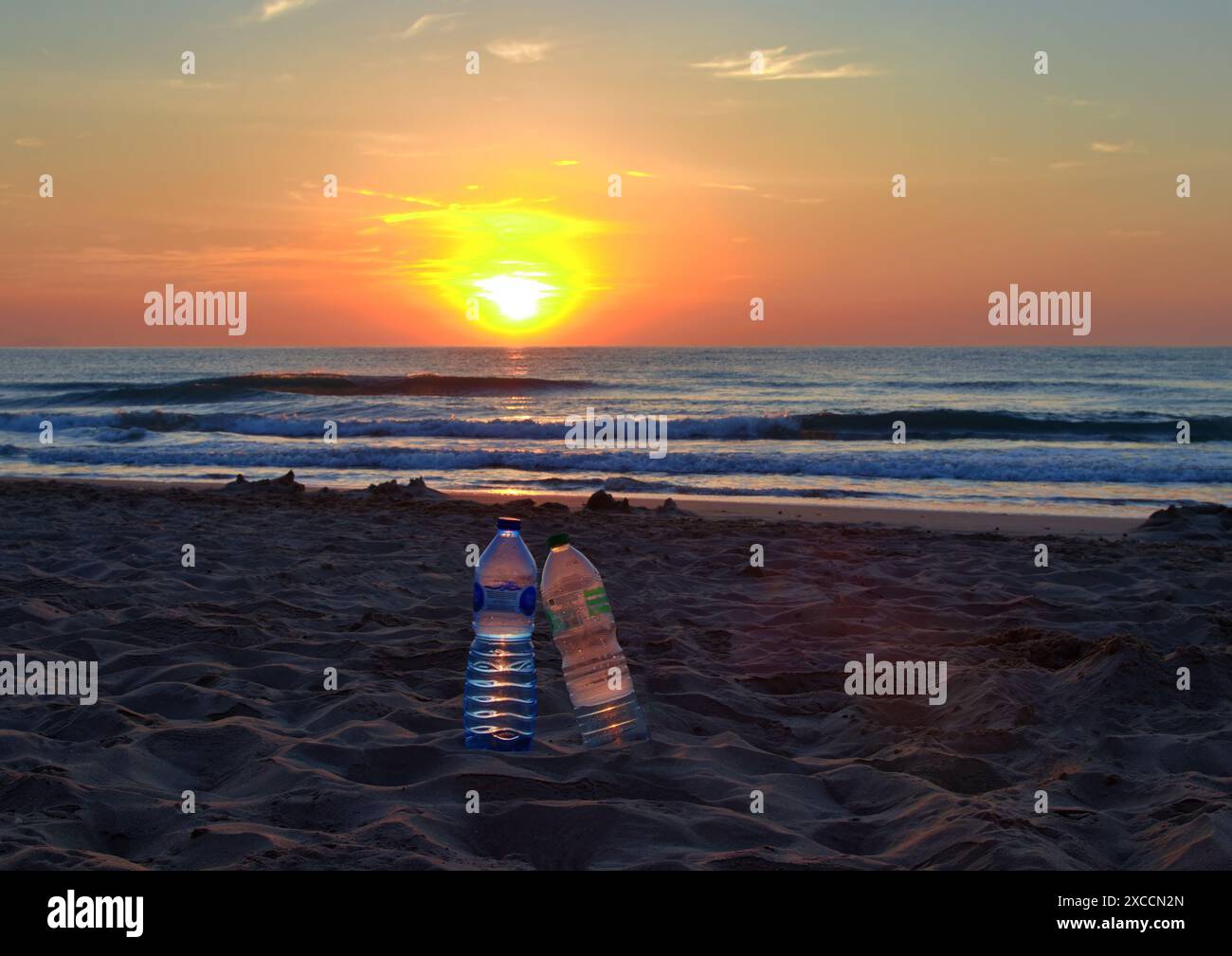 Two plastic bottles on a beach at sunset Stock Photo