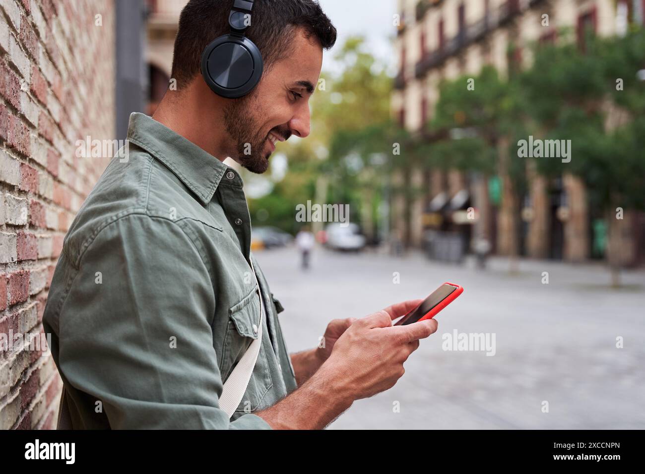 Handsome man relaxing outdoors using phone and listening music in a city street. Stock Photo