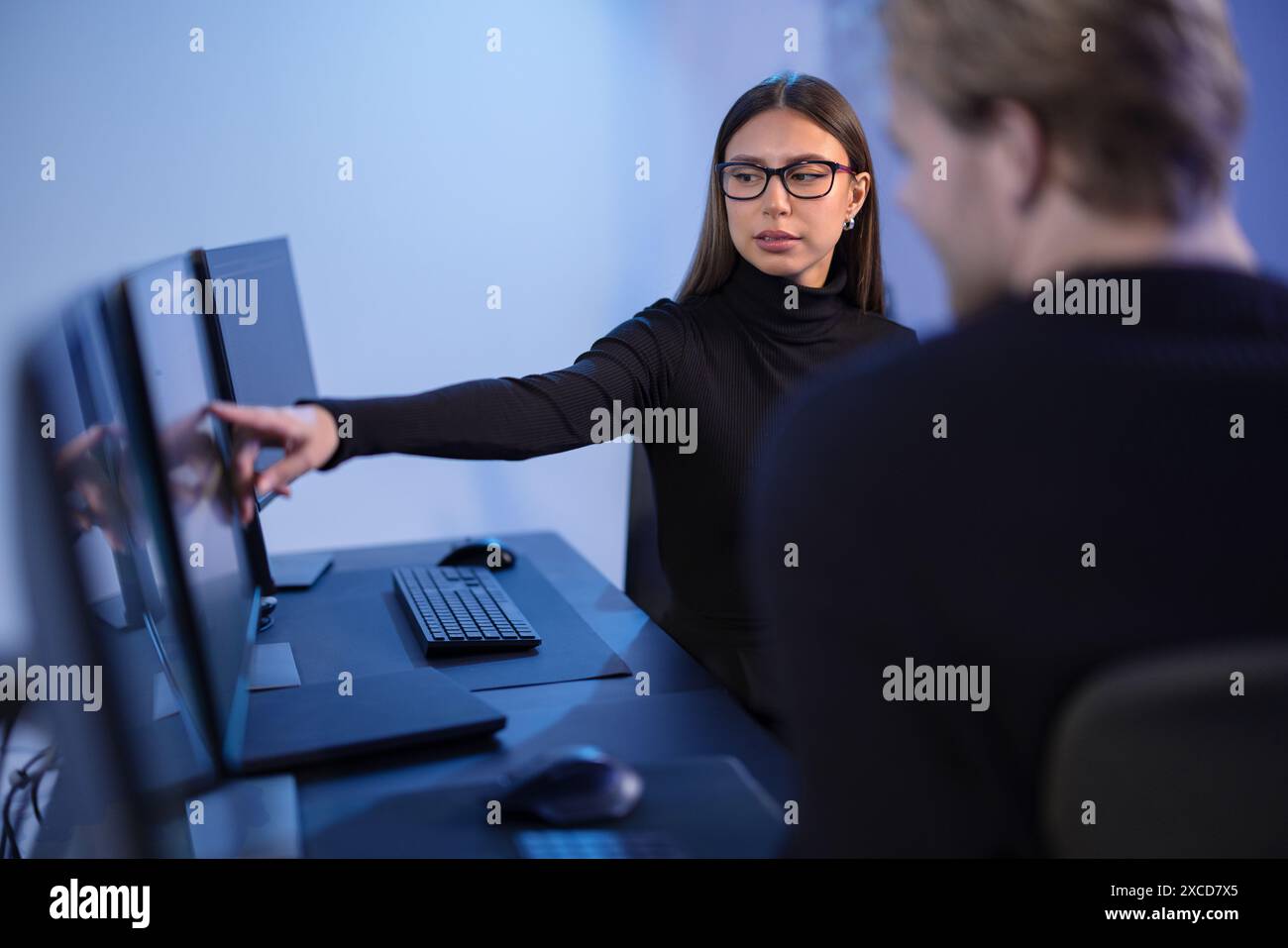 Cybersecurity professionals discussing and analyzing network security data on multiple screens in office Stock Photo