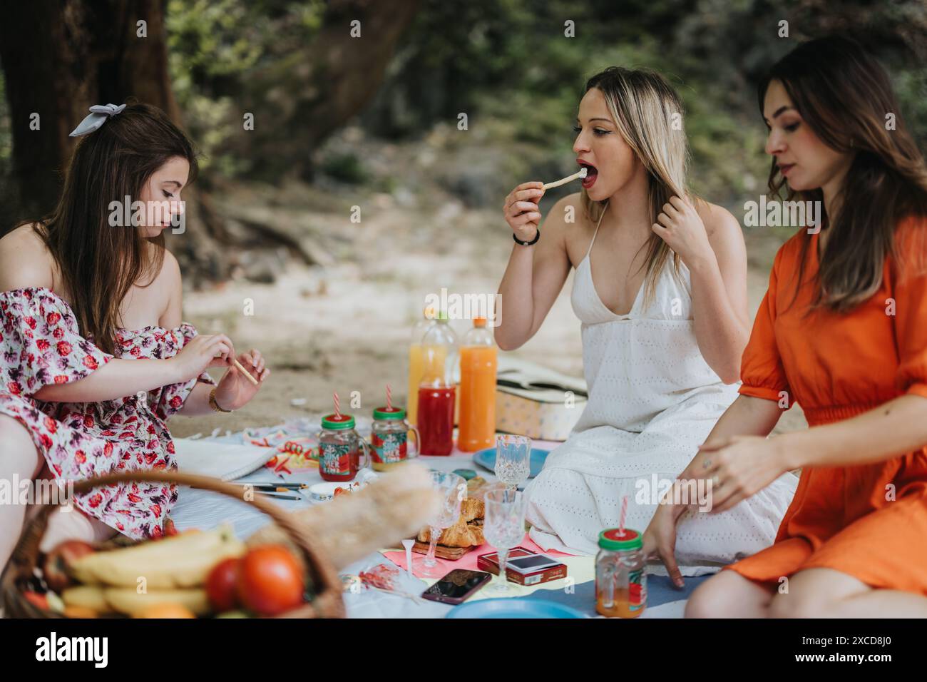 Friends enjoying a picnic with snacks and drinks in an outdoor setting ...
