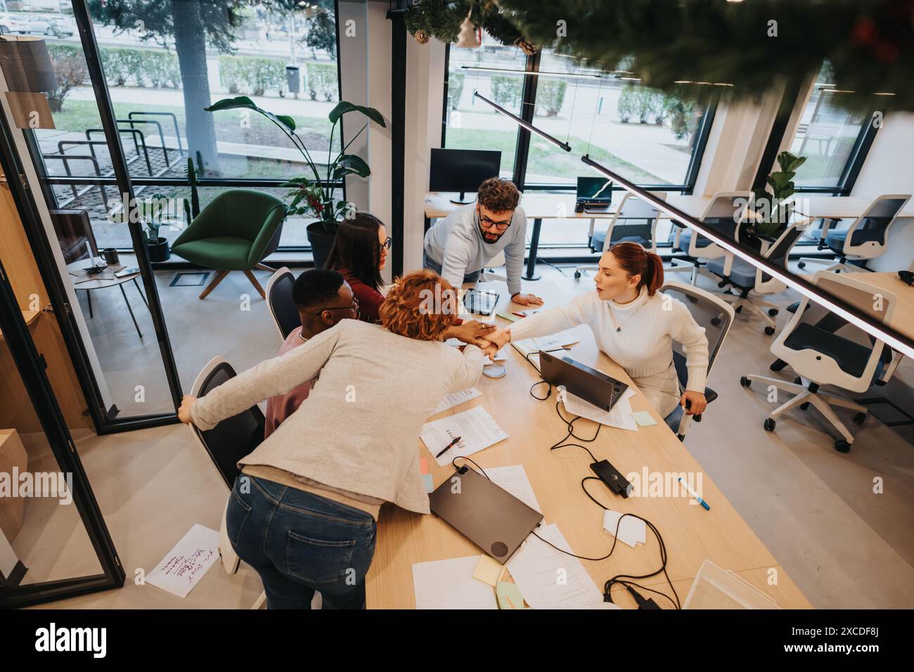 Multiracial team celebrates successful project completion with hands together in victory. Stock Photo