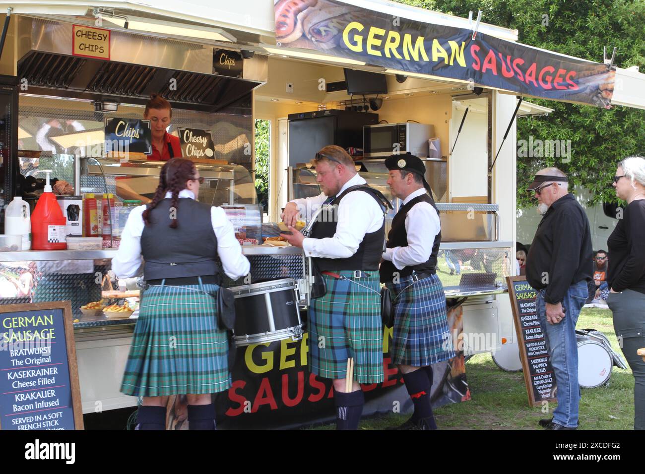 Colchester, UK. 16th Jun 2024. Pipes and drums from across the south of England come together in the Lower Castle Park, Colchester. Medleys of Scottish tunes are being performed together with displays of Highland Dancing. First organised in 1994 the event provides a local contest for pipe bands. Scots buying German sausages. Credit: Eastern Views/Alamy Live News Stock Photo