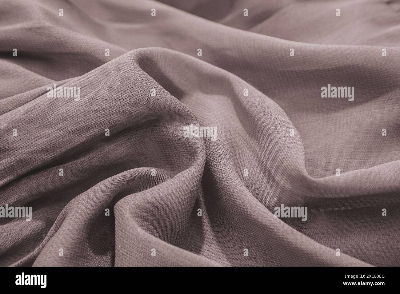 A close-up of pale grayish-brown fabric with soft folds and texture ...