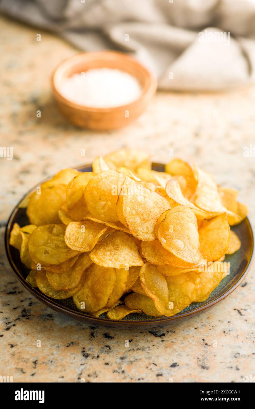 Crispy Potato Chips on plate on a kitchen table. Stock Photo