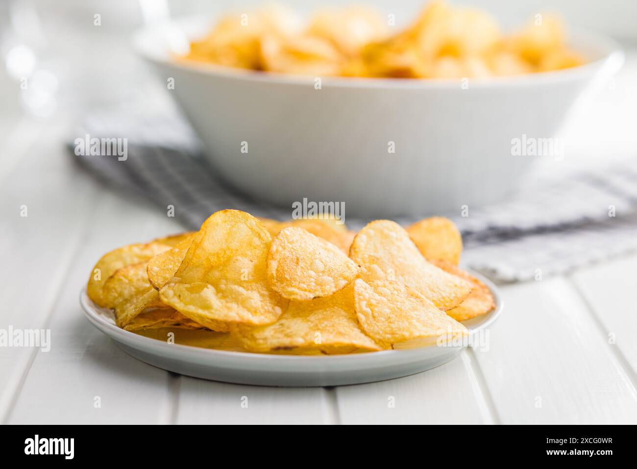 Crispy Potato Chips on plate on a white table. Stock Photo
