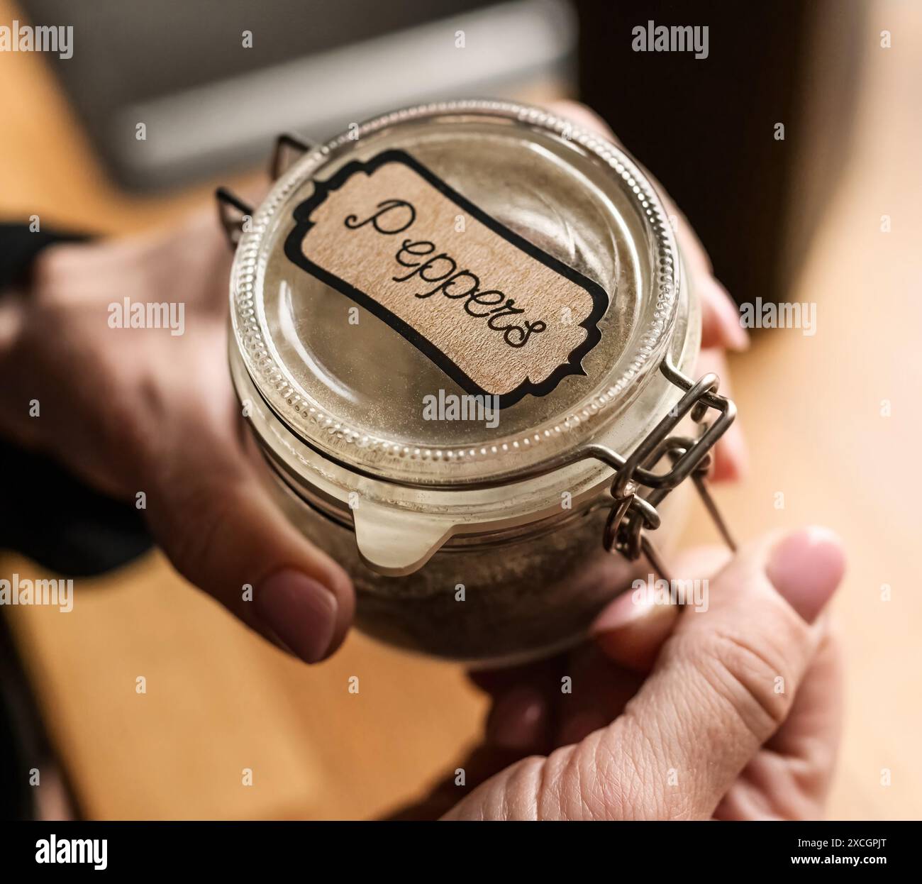 Girl hand opening jar with peppers at kitchen for dish aroma and flavor. Mix of red vegetales for spicy cooking Stock Photo