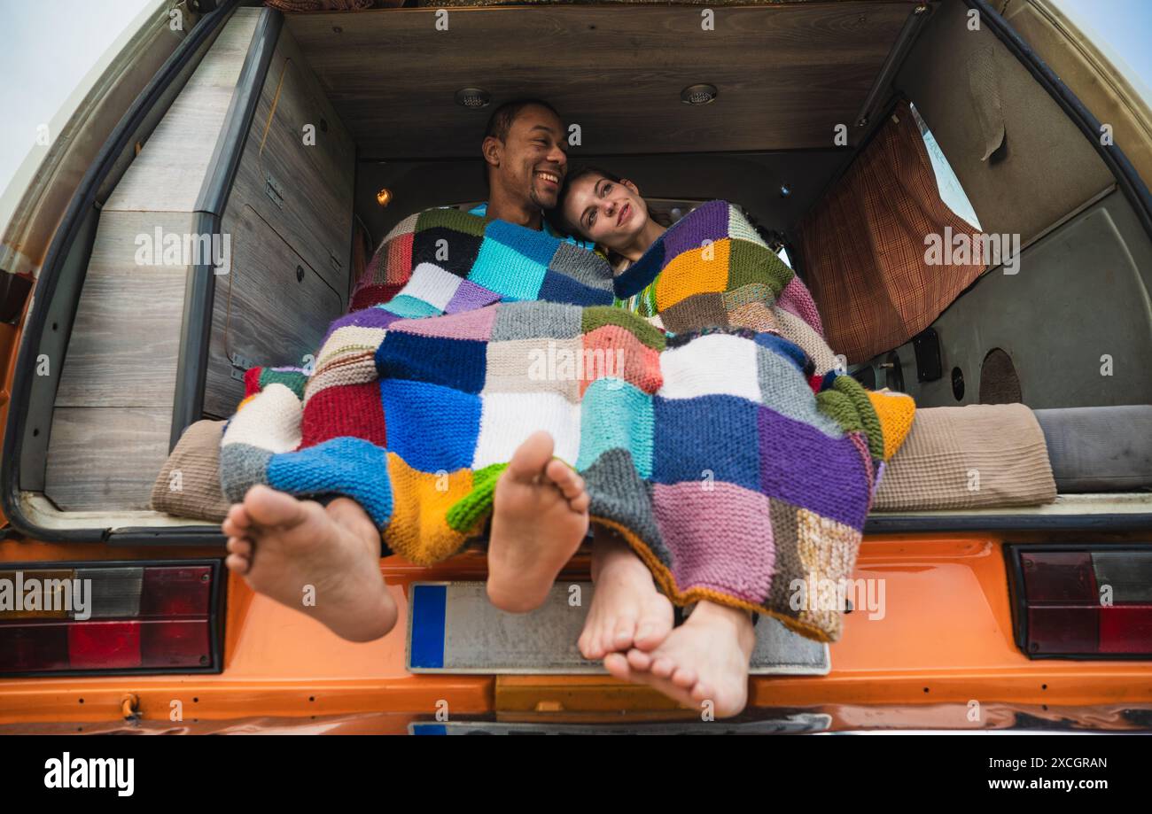 Happy diverse couple sitting in parked van in daylight Stock Photo
