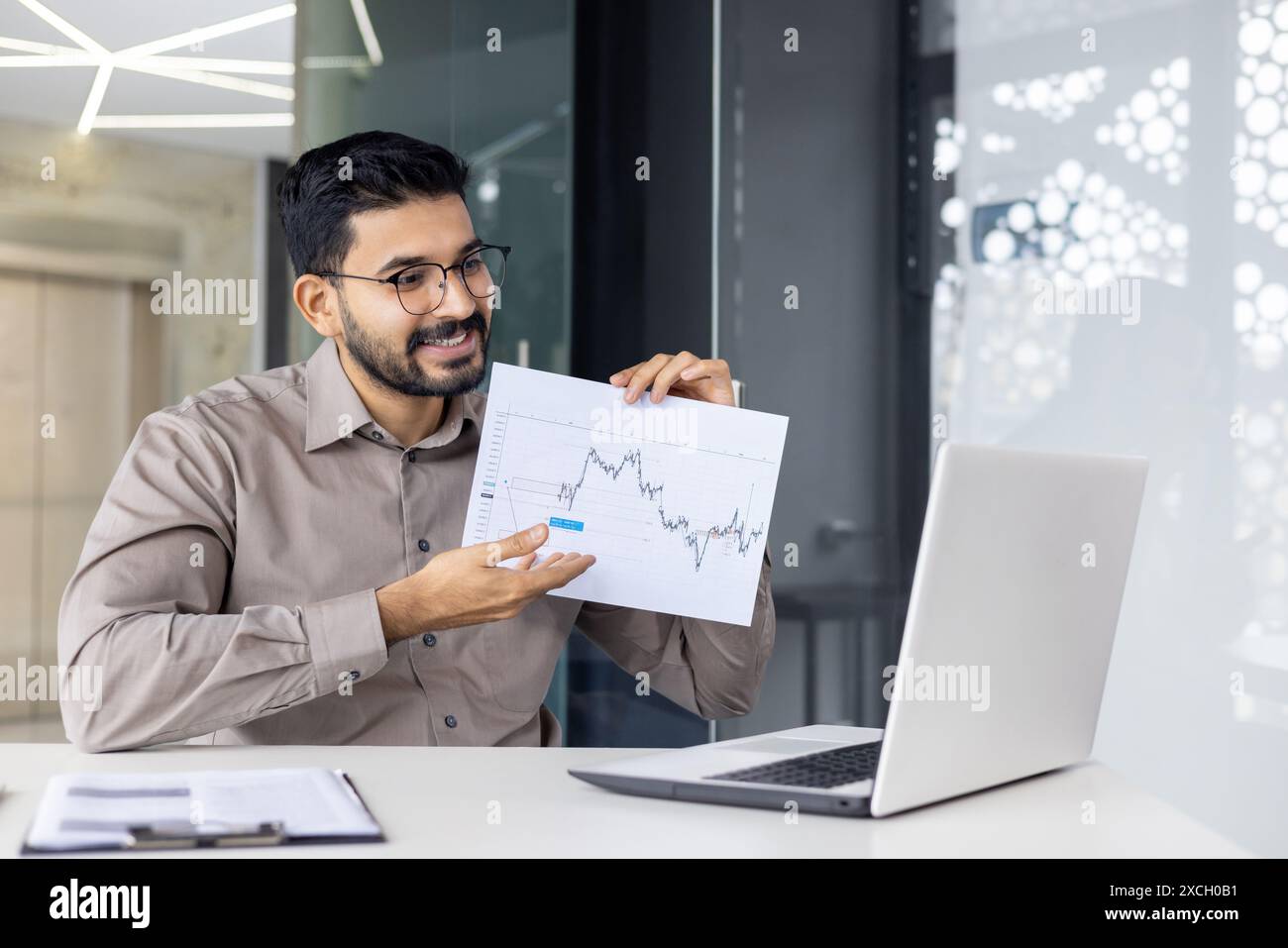 Confident businessman displaying financial chart during an online presentation. Professional discussing market trends in a modern office setting. Stock Photo