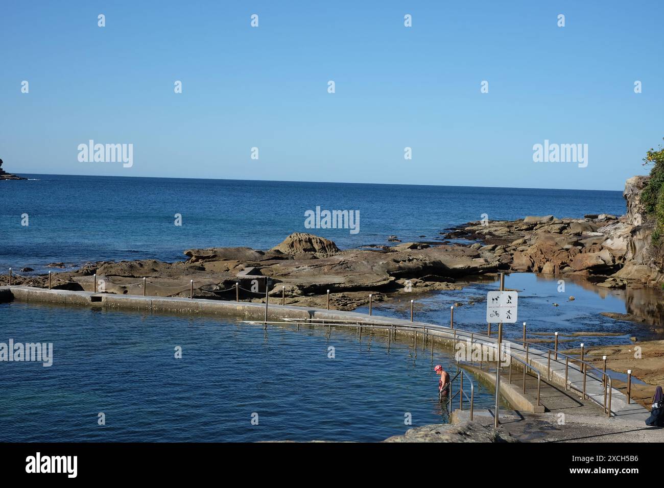 Sydney, Australia, a  Woman entering the ocean pool, at Maroubra, New South Wales, a concrete pool on a bay surrounded by a natural rock shelf Stock Photo