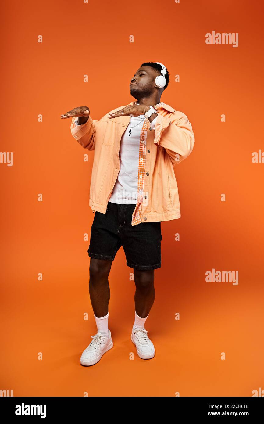 Stylish African American man in orange jacket and shorts against ...