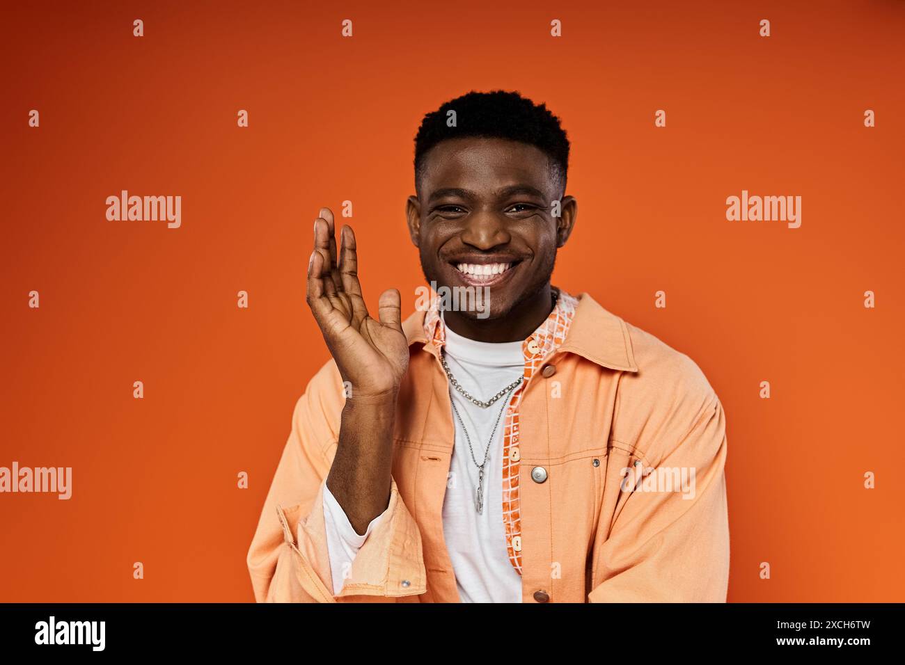 A young man in an orange jacket confidently poses for the camera Stock ...
