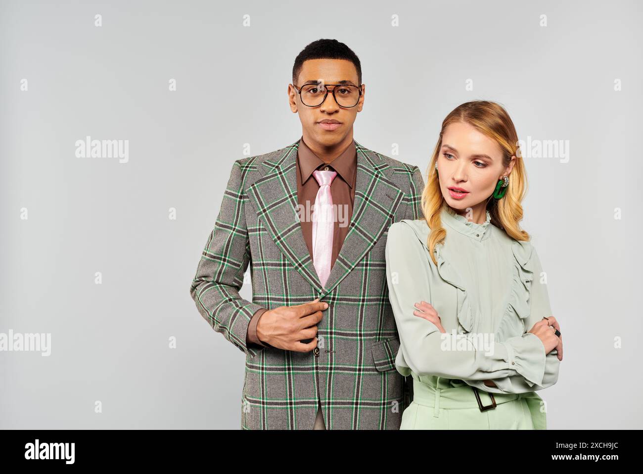 A stylish man and woman in suits strike a pose against a white backdrop ...