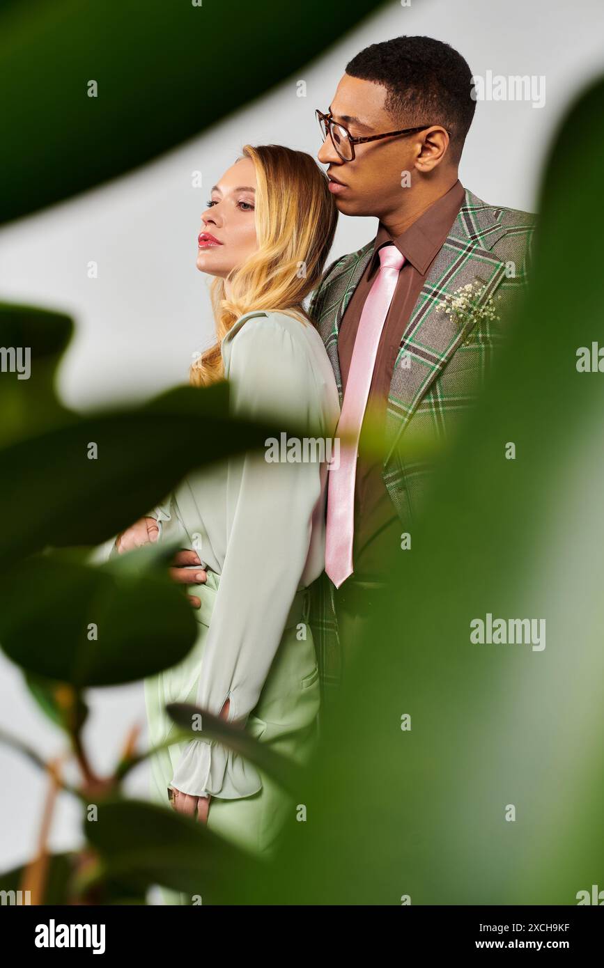 Man and woman strike a loving pose in front of lush green plant Stock ...