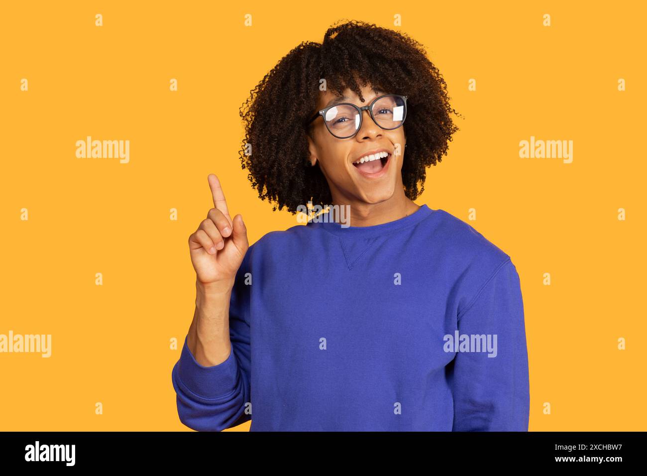 Smiling Young Man With Glasses Points Upward Stock Photo