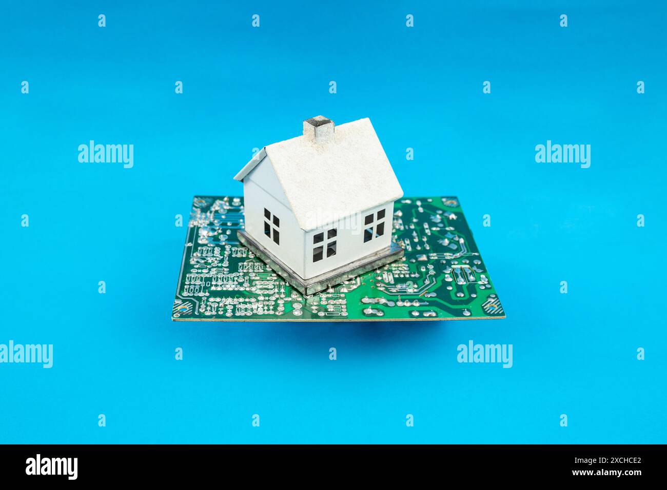 Smart, automated house concept, miniature house connected to a chipset,  on blue Stock Photo