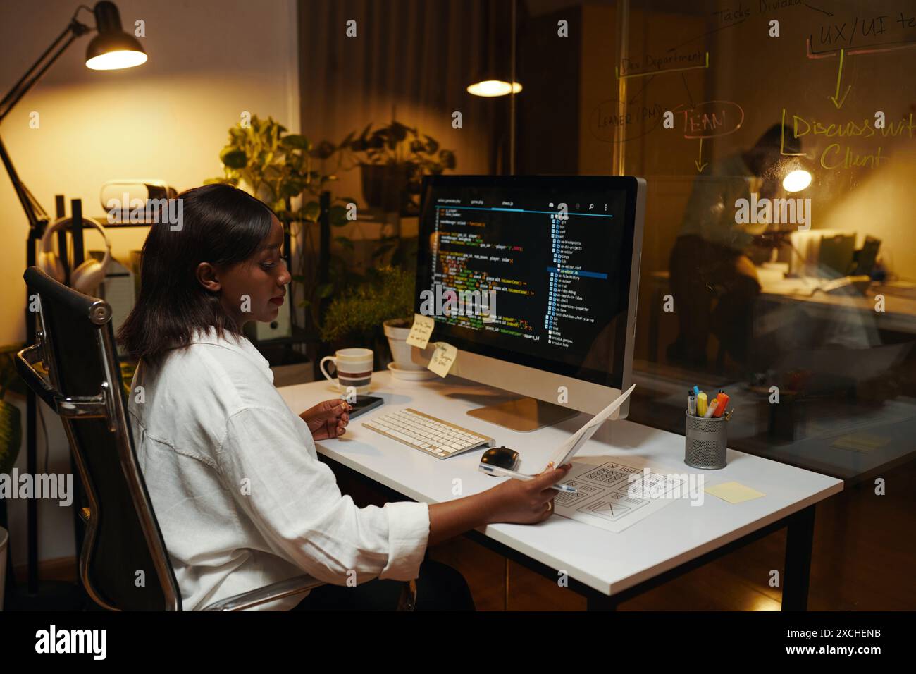 Developer reading document when working on programming code Stock Photo