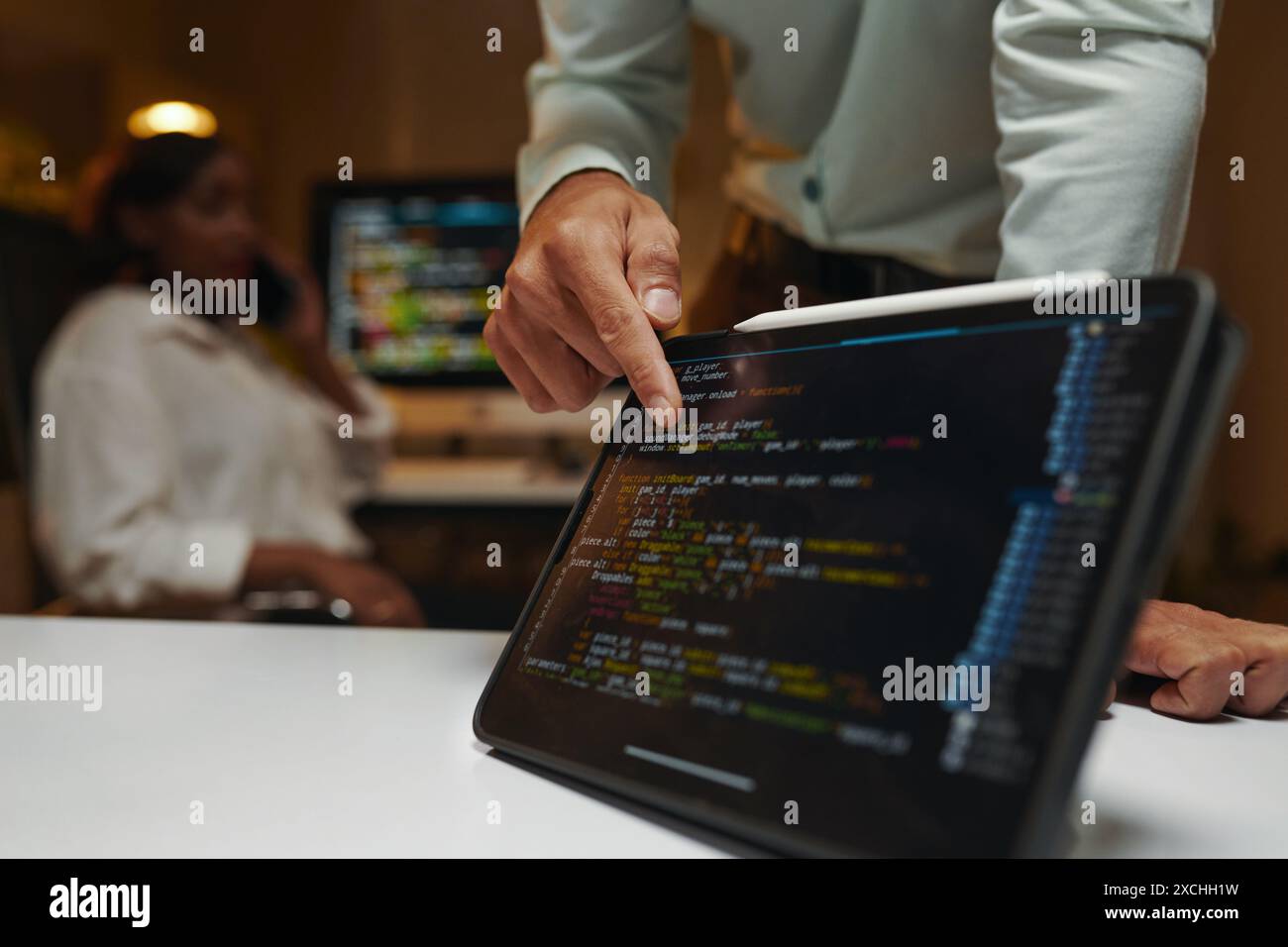 Closeup image of developer pointing at programming code on tablet screen Stock Photo
