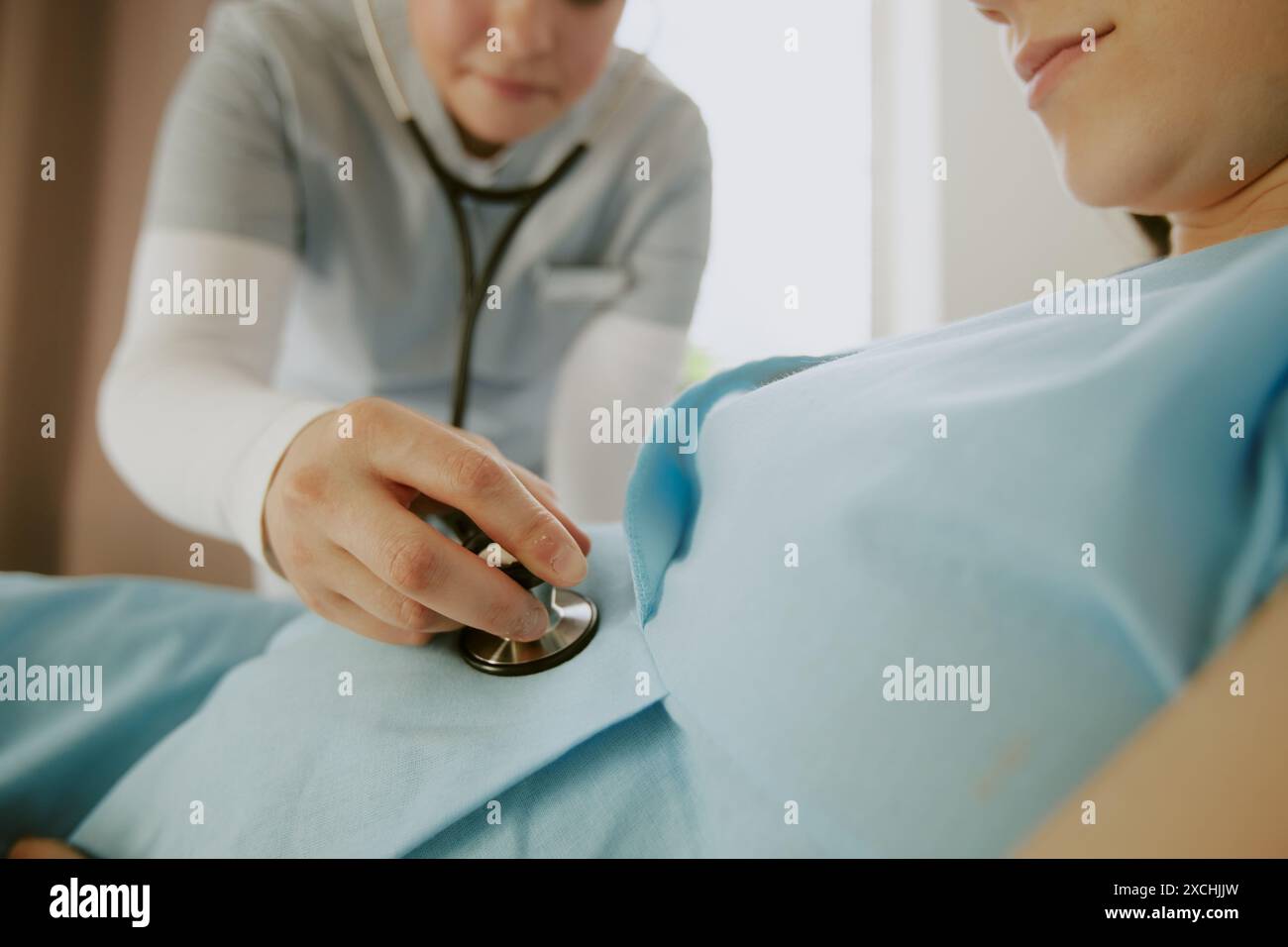 Medium close up of obstetricians hand holding stethoscope on pregnant ...