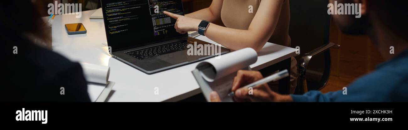 Header with developer showing code on laptop screen in meeting Stock Photo