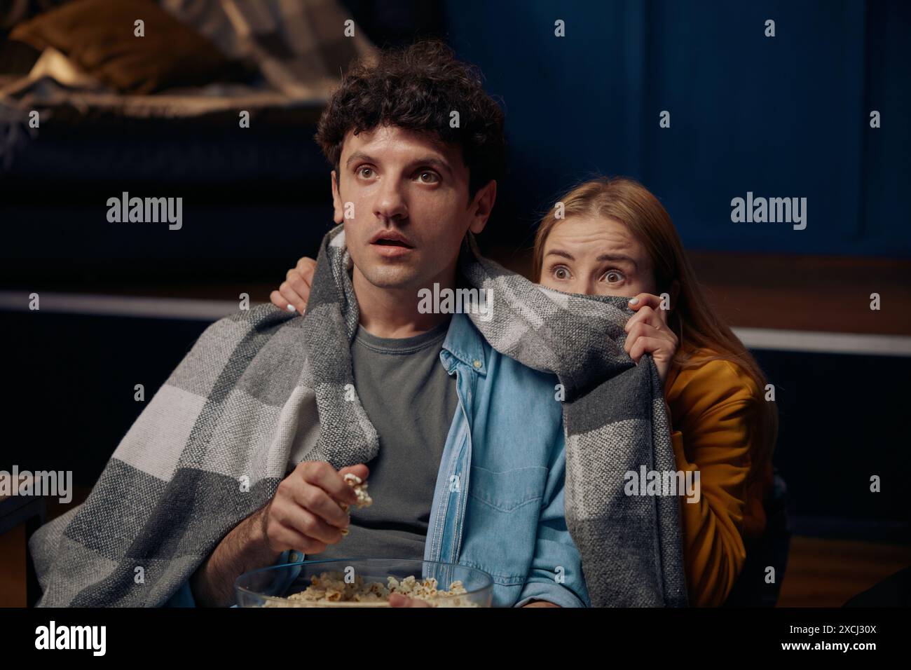 Young couple watching scary movie together Stock Photo