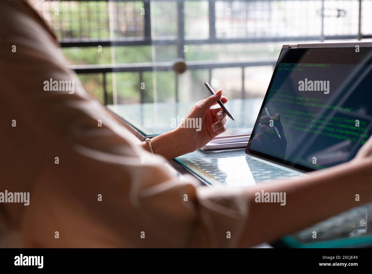 Female freelance developer coding and programming. Coding on two with screens with code language and application. Stock Photo