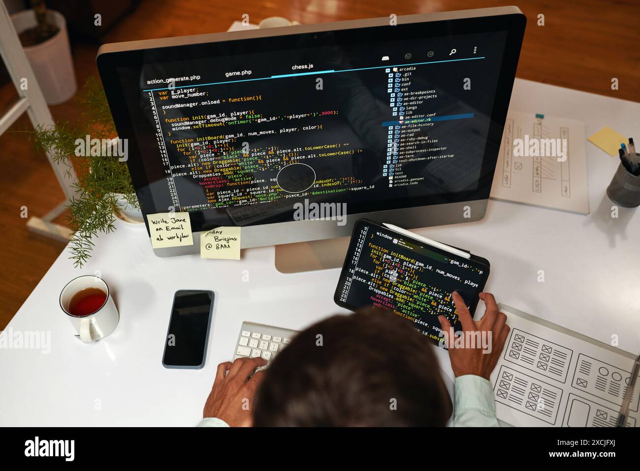 IT specialist reviewing programming code on laptop and tablet computer Stock Photo