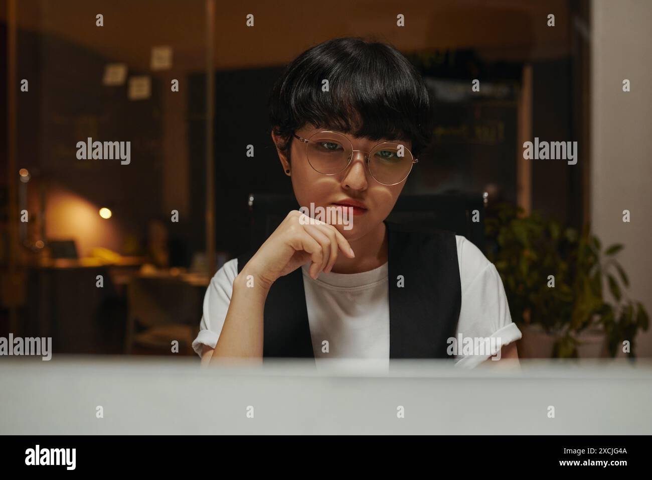 Pensive programmer looking at code on computer screen solving problem Stock Photo