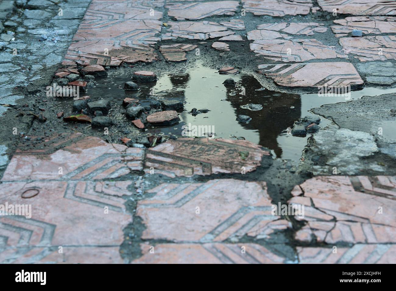 Damaged or broken sidewalk tiles, causing stagnant water. Stock Photo