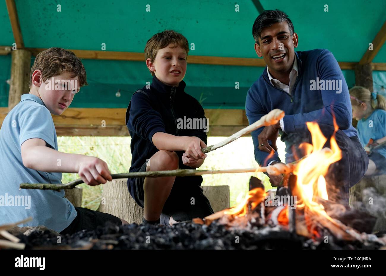 Prime Minister Rishi Sunak toasts bread on an open fire with children