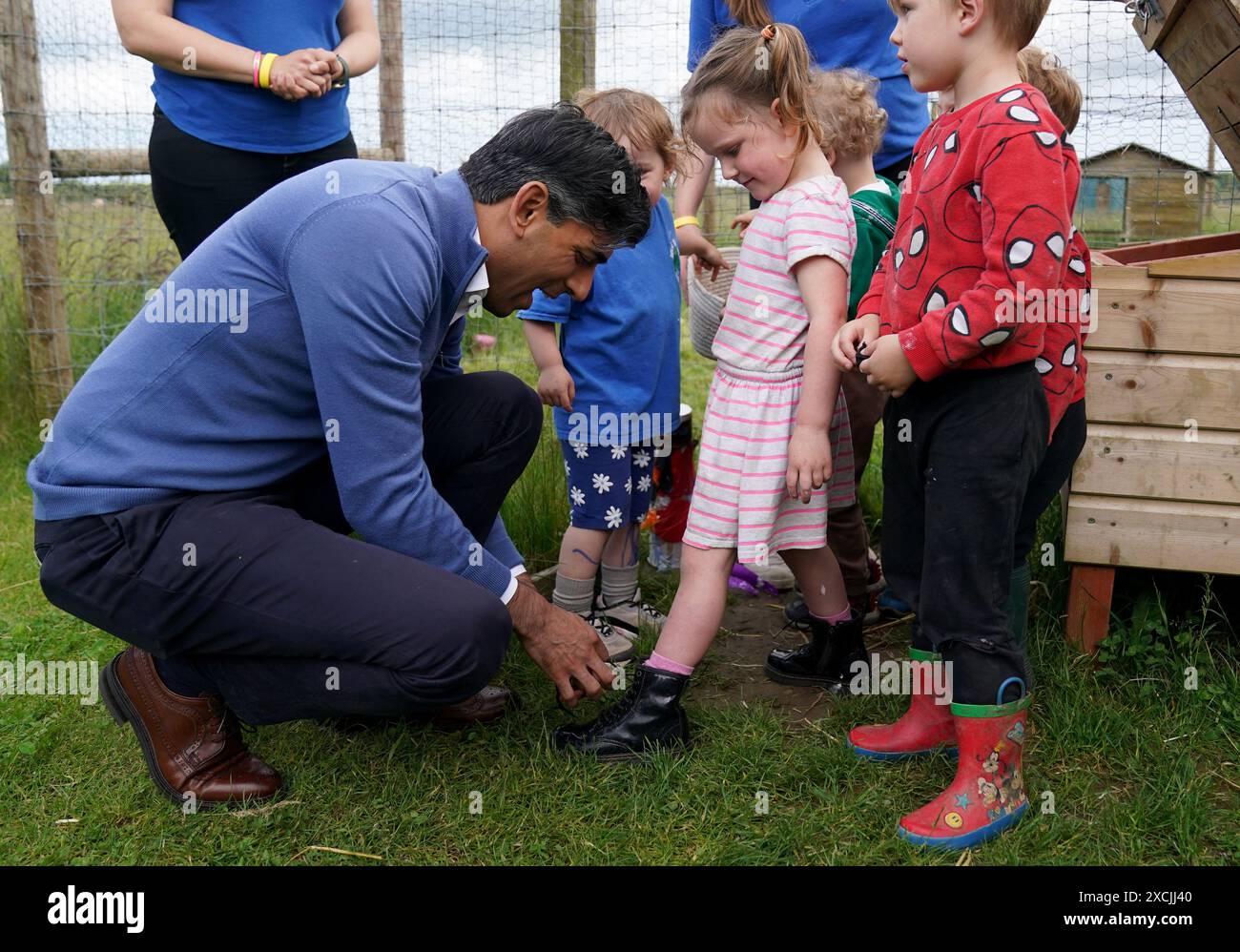 Prime Minister Rishi Sunak helps tie a childs shoe laces during a visit