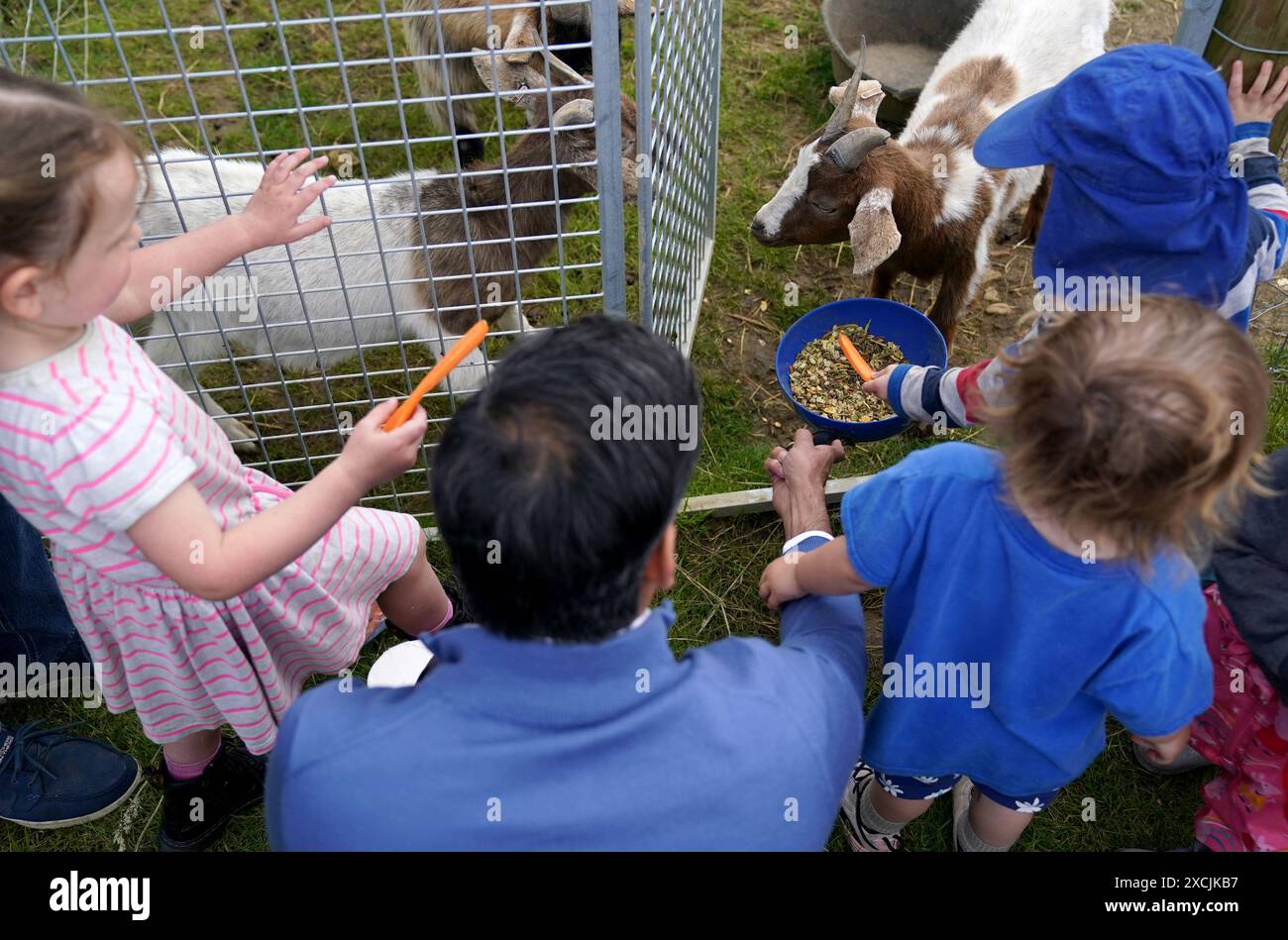 Prime Minister Rishi Sunak helps the children feed the goats during a