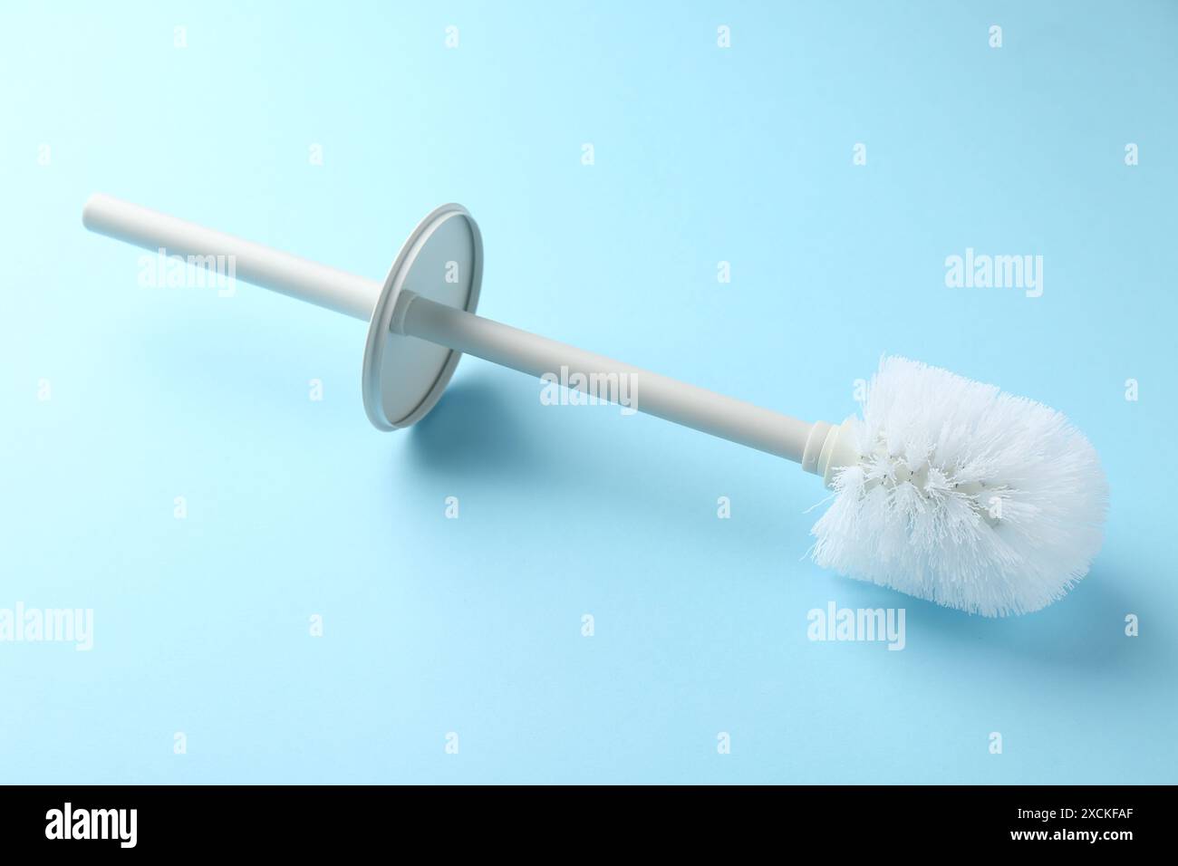 White toilet brush on light blue background Stock Photo - Alamy