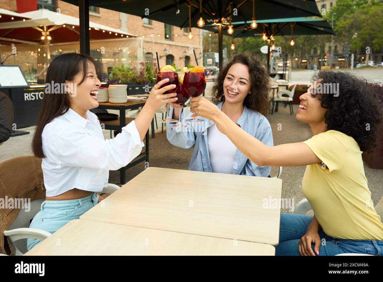Three women are sitting at a table, laughing Stock Photo