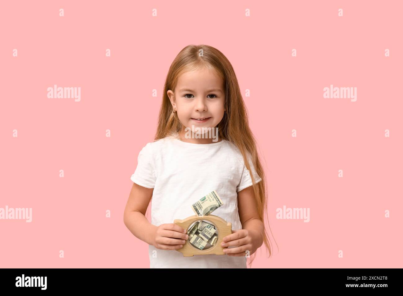 Cute little girl with piggy bank on pink background Stock Photo - Alamy