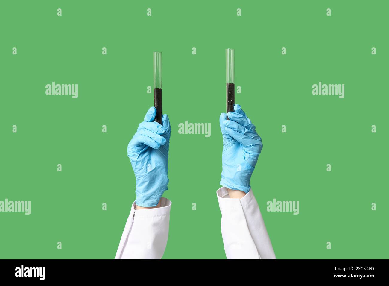 Scientist's hands holding test tubes with soil on green background ...