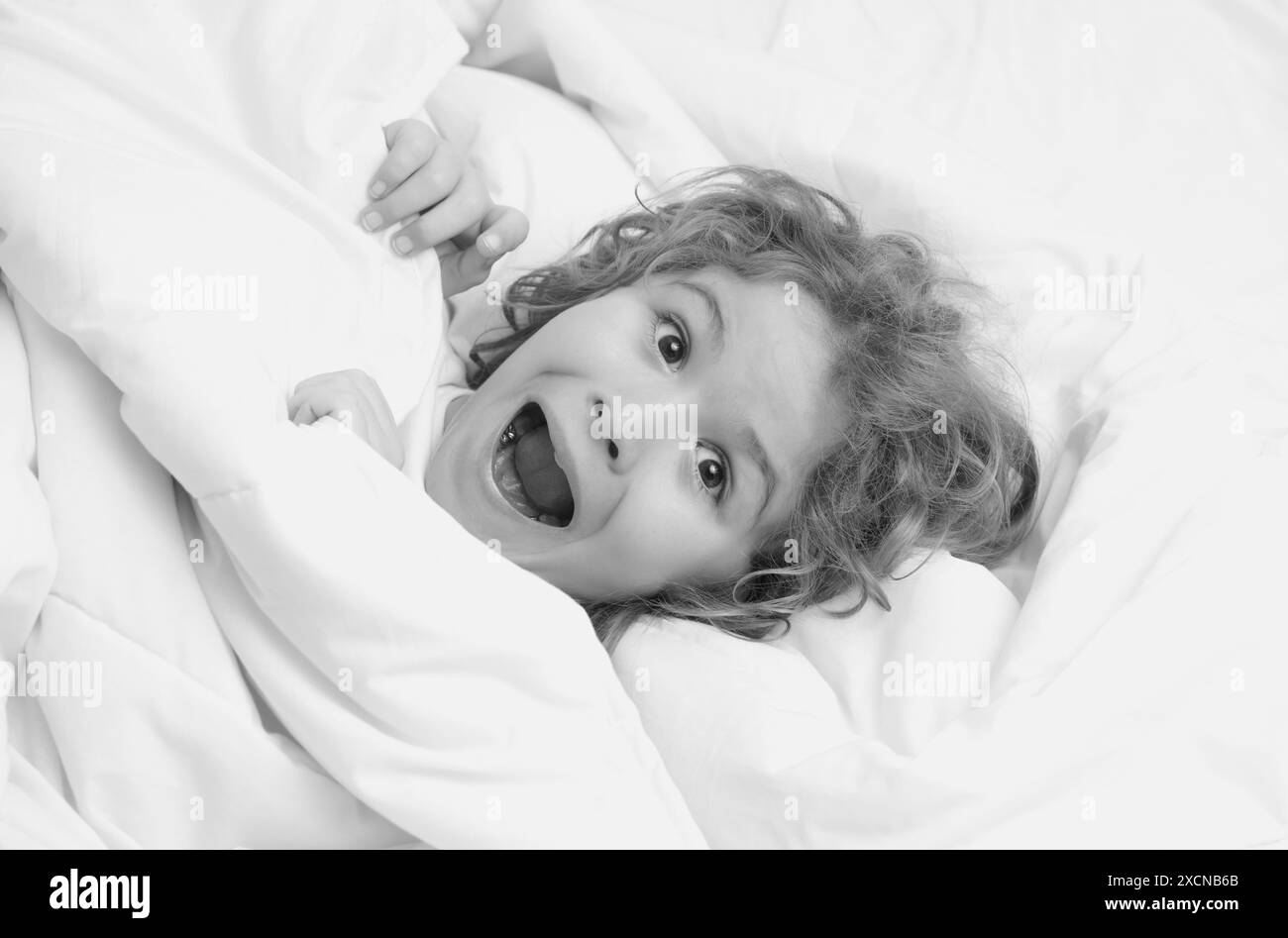 Child wakes up in the morning in the bedroom. Cute little boy waking up