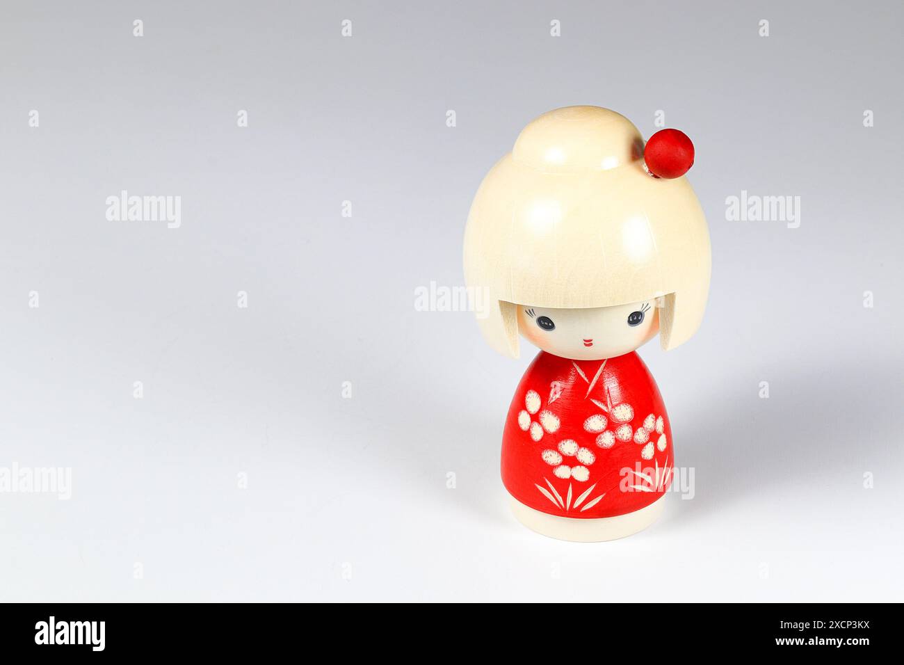 Japanese wooden dolls 'kokeshi' in red Kimono suit, toy for a decoration, souvenir from Japan Isolated on white background. Stock Photo