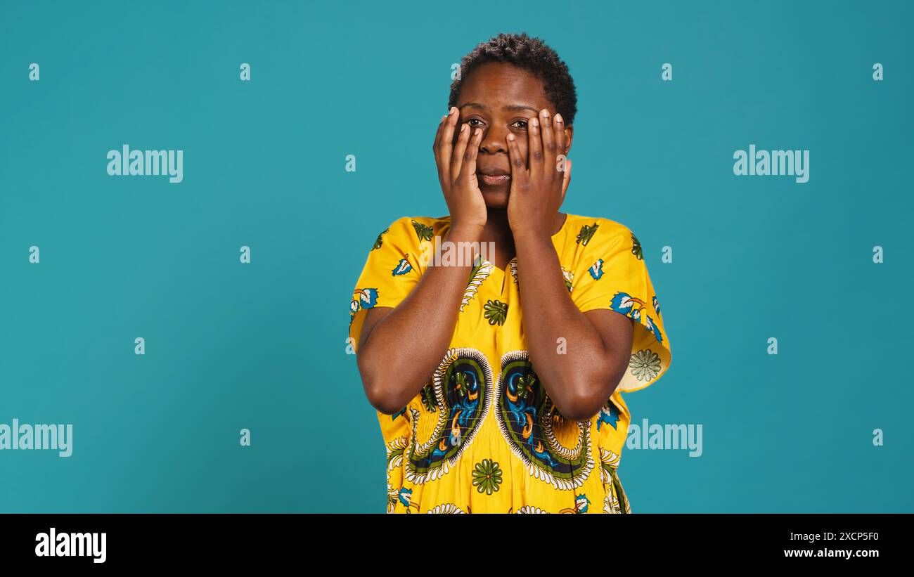 Horrified young woman covering her eyes to avoid seeing something