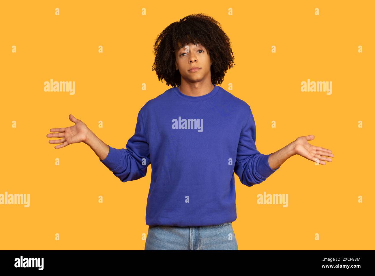 Young Man With Curly Hair Gesturing With Both Hands Stock Photo