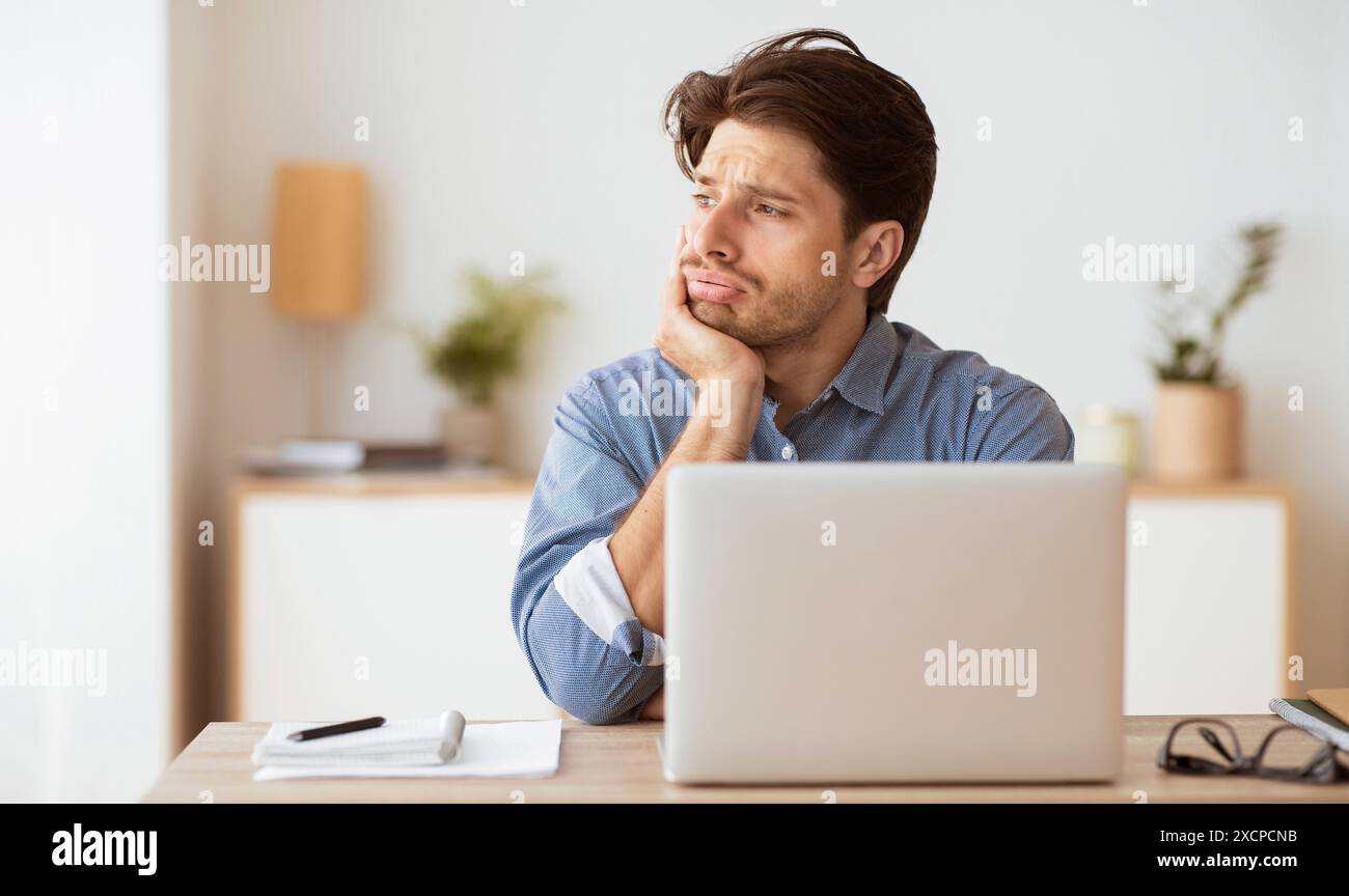 Man Contemplating at Desk With Laptop Stock Photo