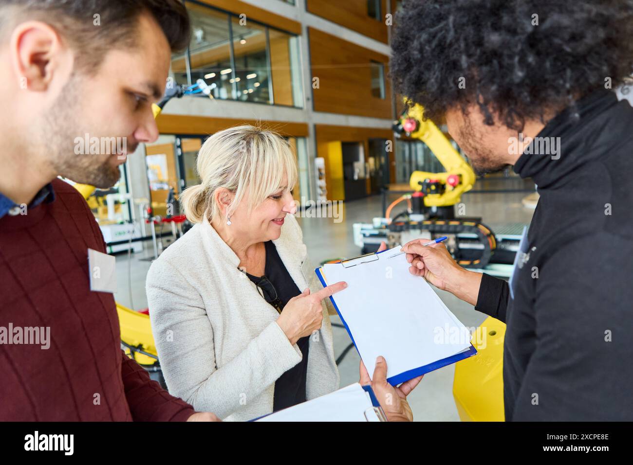 Group of engineers collaborating on robotics programming and development in an industrial environment. Highlighting process automation, teamwork, and Stock Photo