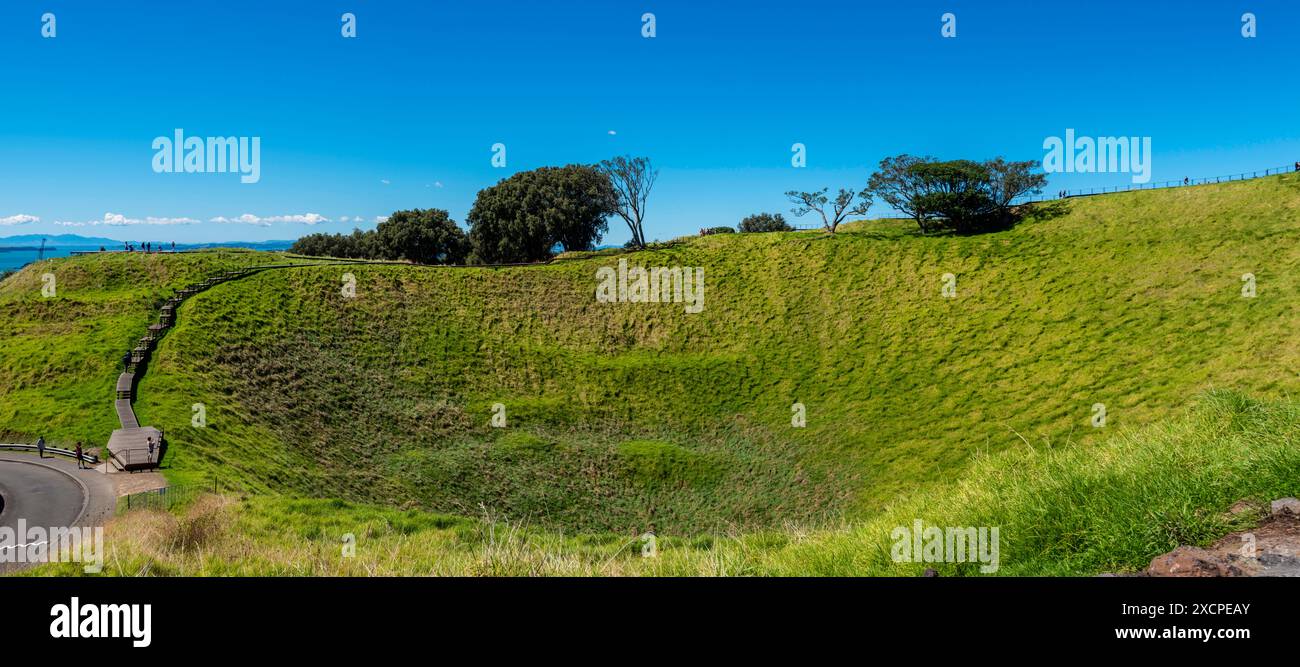 People walking around the dish shaped crater at the centre of the Mt Eden (Maungawhau) Scoria Cone mound that is a dormant volcano in New Zealand Stock Photo