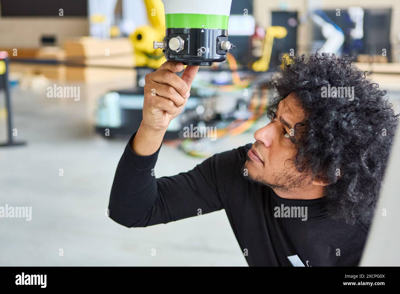 An engineer closely examining a robotic gripper arm in a high-tech workshop, emphasizing advanced robotics and automation technology. Stock Photo