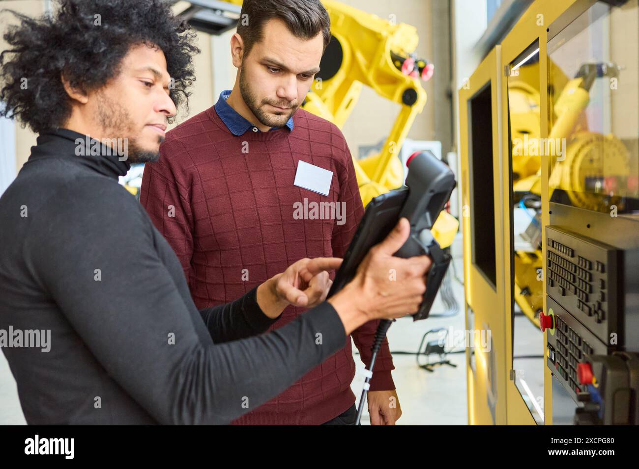 Engineers collaborating on programming an industrial robot using a control panel for precision automation in a modern manufacturing plant. Industry, i Stock Photo