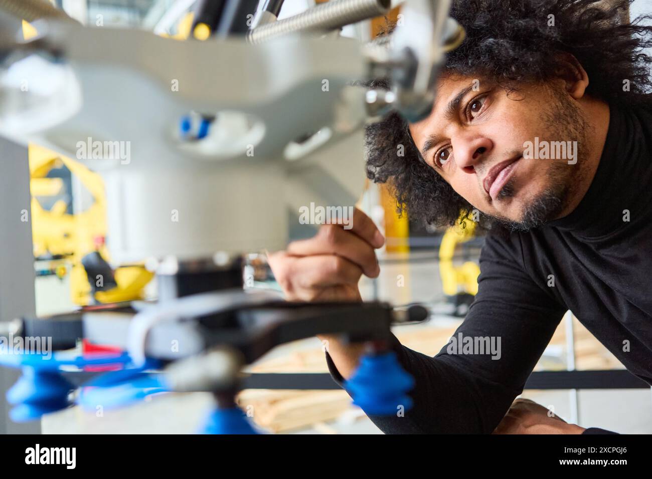 Engineer meticulously examining a robotic gripper arm in a modern robotics lab, focusing on process automation and precision. Stock Photo